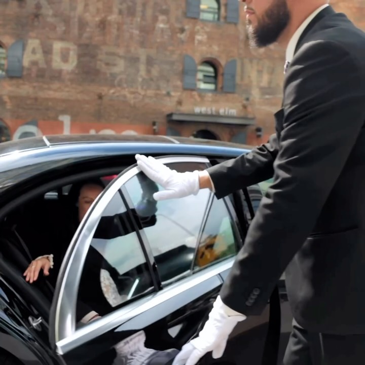 Chauffeur in white gloves opening the rear door of a black luxury sedan in Toronto
